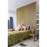 Une chambre aux murs jaunes et un lit.