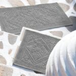 Une paire de paillassons gris sur un sol en pierre.