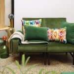 Un canapé vert avec des oreillers colorés dans un salon.