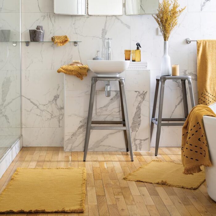 Une salle de bain avec des tapis jaunes et un lavabo blanc.