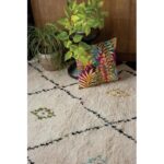 Un tapis blanc avec un oreiller coloré à côté.