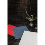 Un tapis de bain rouge et bleu sur un sol carrelé noir.