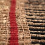 Un gros plan d'un tapis en jute avec une bande rouge.