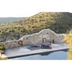 Une piscine avec transats et mur en pierre.