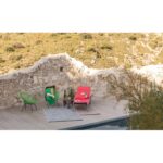 Deux chaises longues sur une terrasse à côté d'un mur.