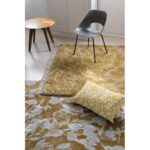 Un tapis jaune et blanc avec un oreiller est posé sur une chaise.