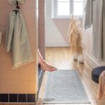 Les pieds d’une femme sont sur un tapis dans une salle de bains.