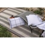 Un tapis d'extérieur à rayures avec des oreillers.