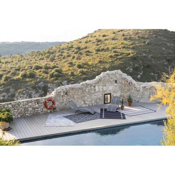 Une piscine avec transats et mur en pierre.