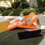 Une chaise longue orange dans un jardin.