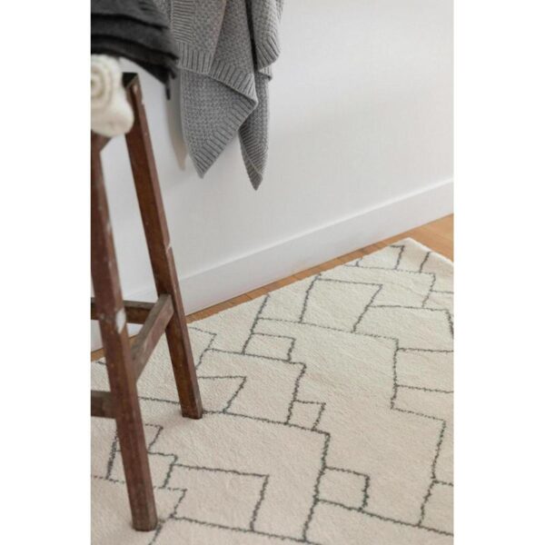 Tapis beige à motifs géométriques avec tabouret en bois.