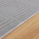 Tapis gris géométrique sur plancher bois.