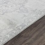 Tapis gris à motifs, sol en bois foncé.