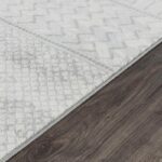 Tapis blanc géométrique sur sol en bois brun.