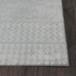 Tapis gris motifs géométriques sur sol boisé.