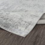 Tapis gris moderne sur parquet brun.