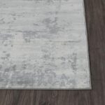 Tapis gris moderne sur parquet brun.