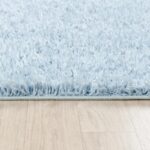 Tapis moelleux bleu clair sur parquet.