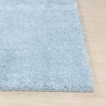 Tapis moelleux bleu sur plancher en bois.