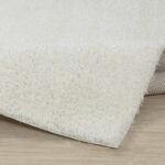 Tapis blanc doux et moelleux sur sol clair.