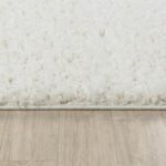 Tapis blanc moelleux sur sol stratifié.