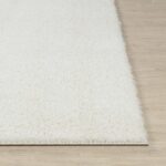 Tapis blanc moelleux sur sol en bois.
