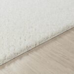 Tapis blanc moelleux sur plancher en bois.