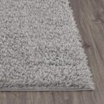 Tapis shaggy gris sur plancher en bois.