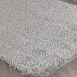 Tapis gris moelleux sur plancher en bois.