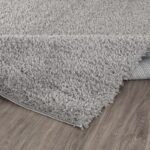 Tapis gris moelleux sur parquet brun.