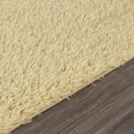 Tapis moelleux beige sur plancher en bois.
