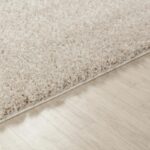 Tapis moelleux beige sur parquet clair.