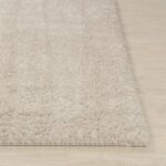 Tapis doux beige sur plancher en bois.