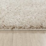 Tapis moelleux beige sur parquet clair.
