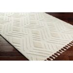 Tapis beige à motifs géométriques et franges.