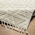 Tapis blanc à motifs géométriques et franges décoratives.