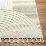 Tapis à franges beige sur parquet bois.