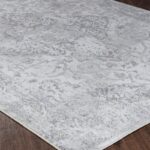 Tapis gris à motifs sur parquet brun.
