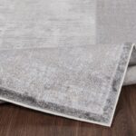 Tapis gris enroulé sur plancher bois.