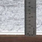 Règle métallique mesurant tapis blanc.