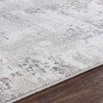 Tapis moelleux gris et crème sur parquet.