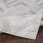 Tapis beige motif géométrique sur plancher bois.