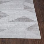 Tapis moderne gris à motifs géométriques sur parquet.