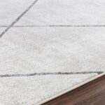 Tapis blanc géométrique sur plancher bois.