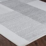 Tapis moderne gris à motifs géométriques sur parquet.