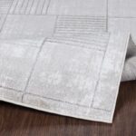 Tapis gris moderne sur plancher en bois.