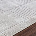 Tapis texturé gris sur sol en bois.