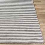 Tapis rayé gris et blanc sur parquet.