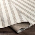 Tapis rayé beige enroulé sur plancher en bois.