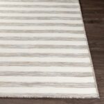 Tapis rayé beige sur plancher en bois.